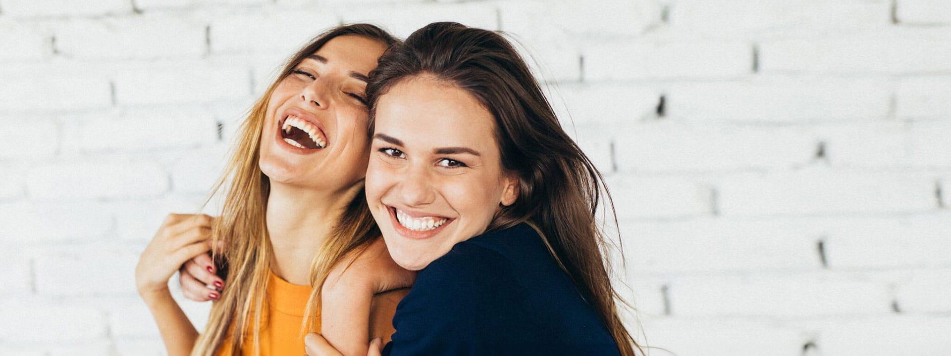 Two female friends laughing with amazing smiles